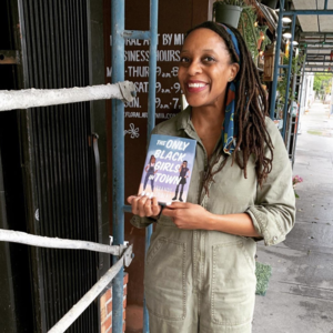 Picture of Brandy Colbert holding up 'The Only Black Girls in Town' outdoors