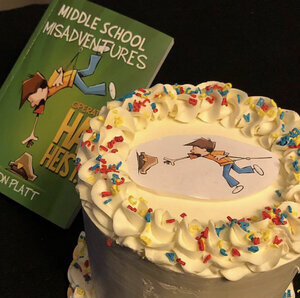Jason Platt's book 'Middle School Misadventures' next to a cake with the cover of his book on the cake top
