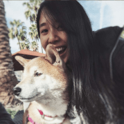 Picture of Julie Abe and a dog, outside, with palm trees in the background