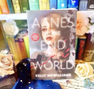 Picture of 'Agnes at the End of the World' on a bookcase surrounded by books and roses