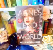 Picture of 'Agnes at the End of the World' on a bookcase surrounded by books and roses
